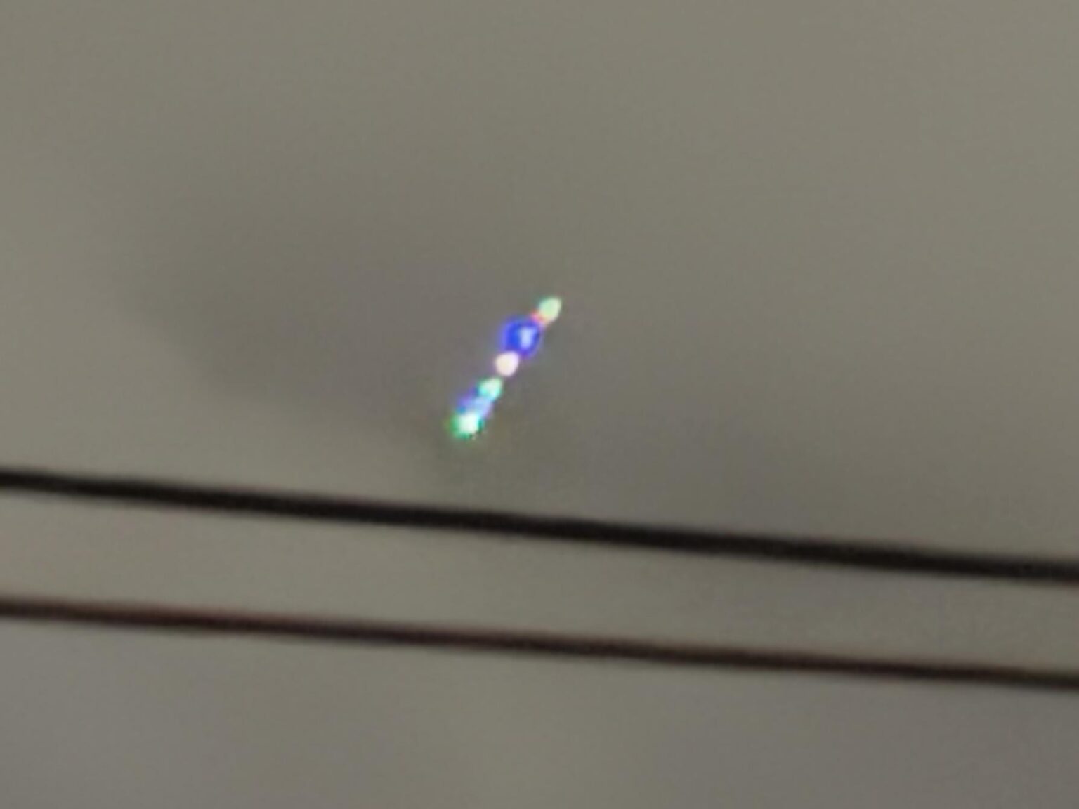 Row of lights in night sky, blinking different colors. East Coast US.