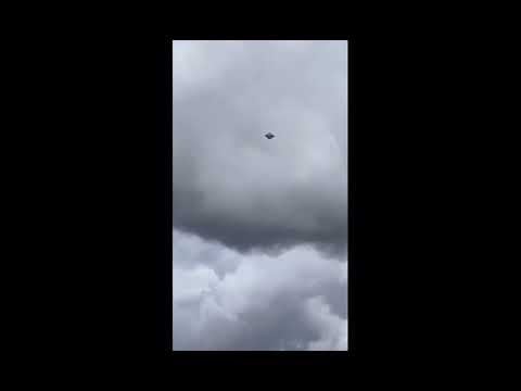 Alien craft hovers over a city. Is this also in Colombia? The craft appears to hover silently. No visible means of propulsion. No movement. No sound. Strange diamond shape. Not human tech.