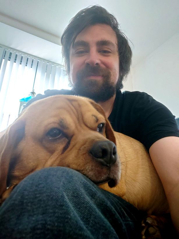 mark smiling with dog resting his head on his knee