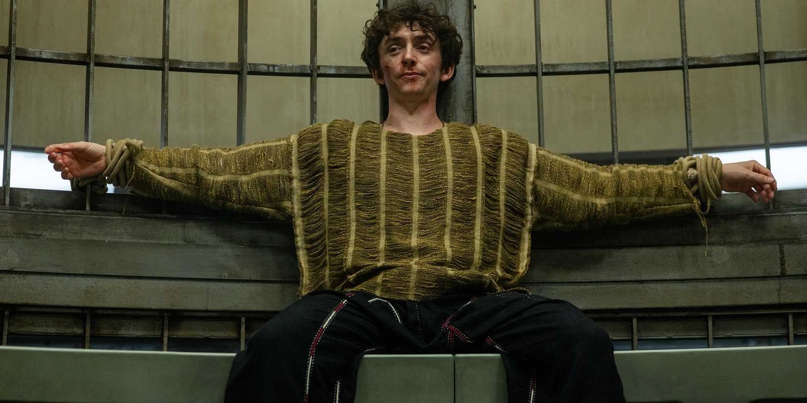 Samuel Blenkin's Boy Kavalier smiling smugly while tied up in a cell in Alien: Earth season 1 episode 8