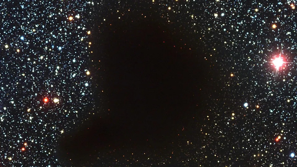  A photograph of starry outer space with a dark blob in the middle. 