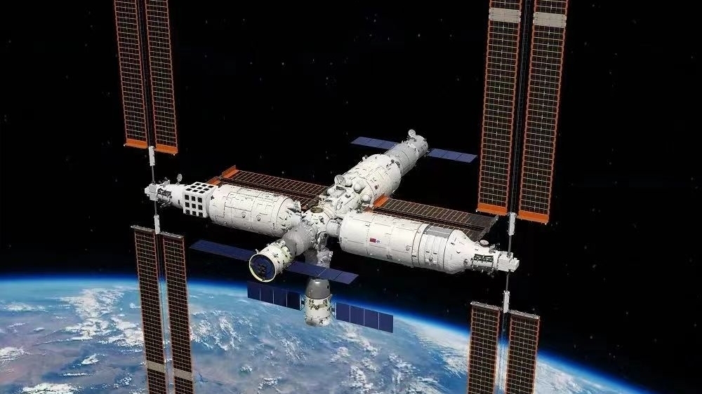 A photo of a large space station with arrays of solar panels floating above Earth