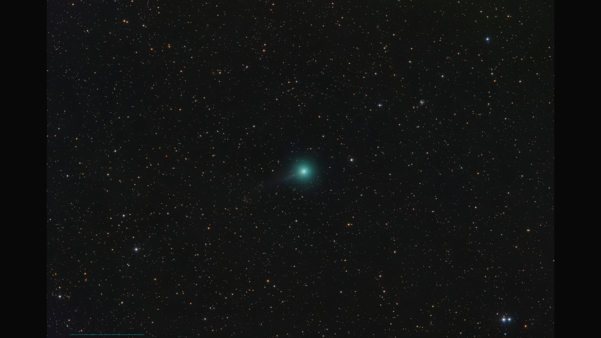 A bright green comet is pictured to the bottom left of a starfield against a black sky, with a long tail extending to the upper right of the screen.