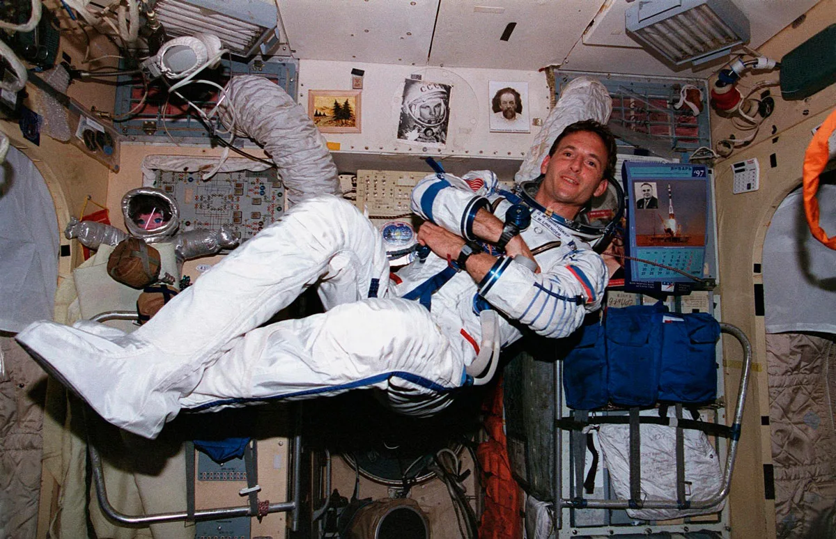 A man in a space suit floats in a space station.