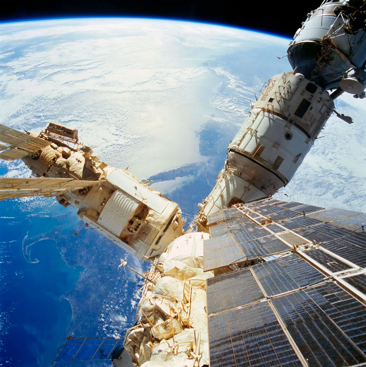 As photographed from the overhead Windows on the aft flight deck of the docked Space Shuttle Atlantis, a number of components of the cluster comprising the Russia's Mir Space Station are backdropped over the northeastern United States.
