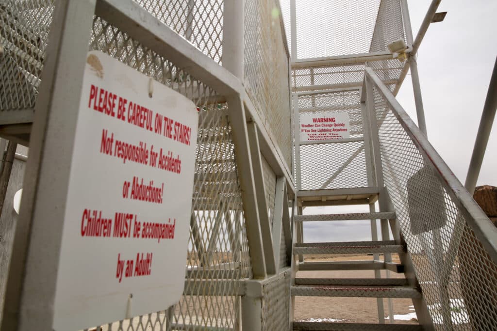 Signs on the stairs up the metal scaffolding of the UFO Watchtower warn visitors to take care on the steps and watch for lightning.