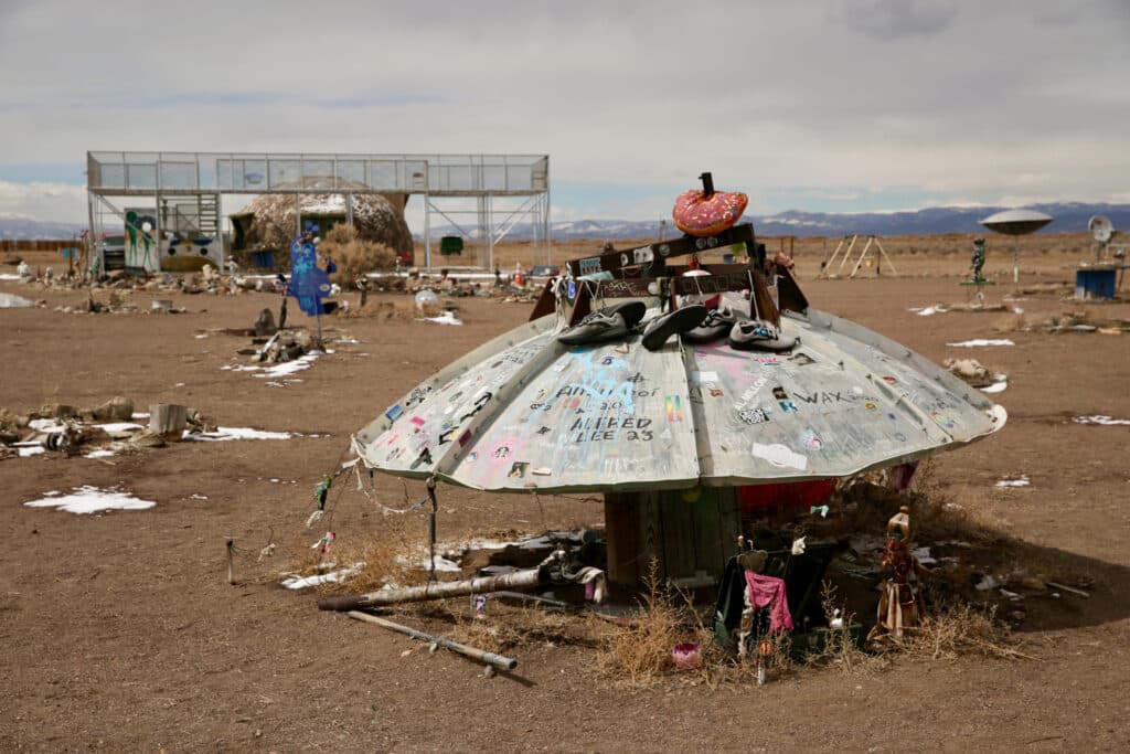 An overturned satellite dish is littered with shoes, stickers and other trinkets at the UFO Watchtower tourist attraction.