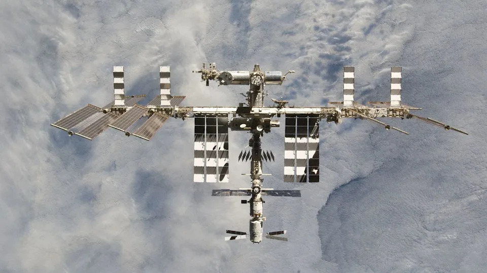  A photo of a large space station with various solar panels floating above Earth. 