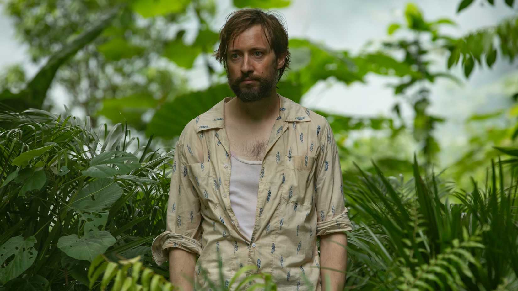 Arthur (David Rysdahl) stands in the middle of the rainforest, looking deflated.