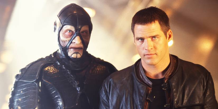 Two characters stand in a corridor and look ahead with serious expressions in Farscape.