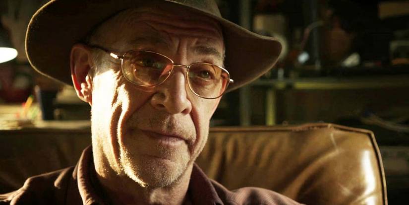 J.K Simmons wears a hat and glasses while looking on in conversation in Dark Skies