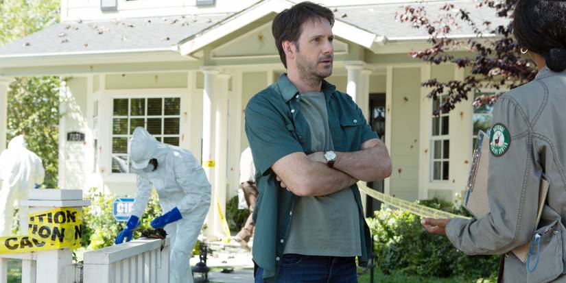A man talks to authorities while people in hazmat suits work in his yard in DARK SKIES