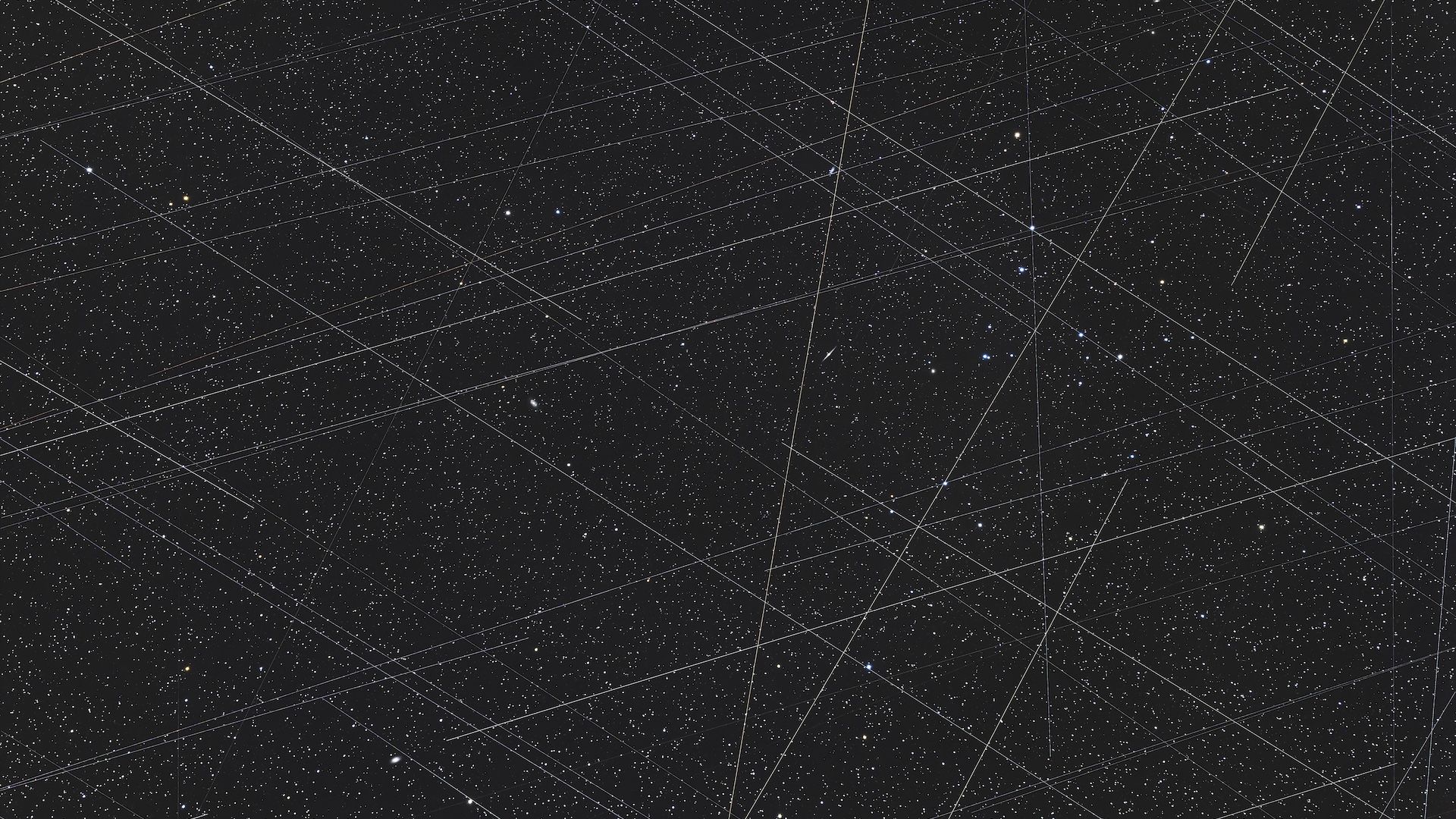 Photo of the night sky with zig-zagging streaks left by satellites