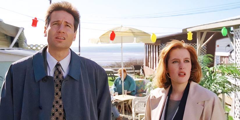 Mulder and Scully look up as they stand at an outdoor beach restaurant in The X-Files.
