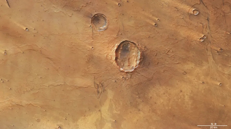 A photo of the surface of Mars from space, with a large crater seen in its reddish brownish surface