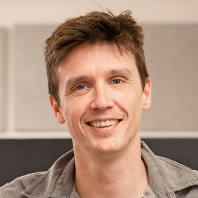 A person smiles for a headshot in a classroom setting.