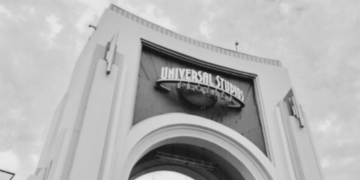 A black and white photo of the entrance archway to Universal Orlando, featuring the large iconic sign