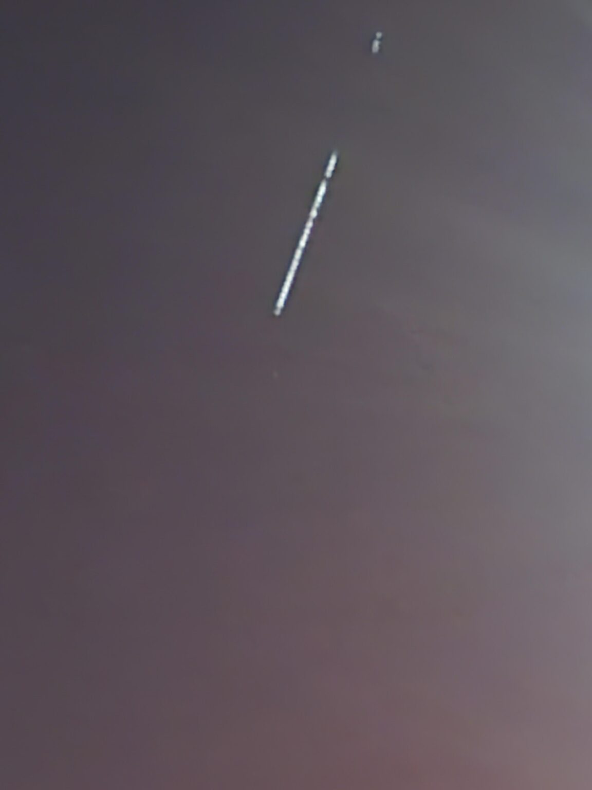 Hundreds of small lights in a single file line high up in the sky