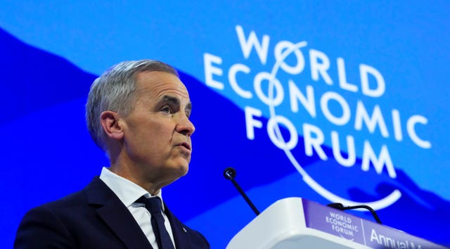 Mark Carney making a speech in front of a blue backdrop featuring the words 'World Economic Forum'