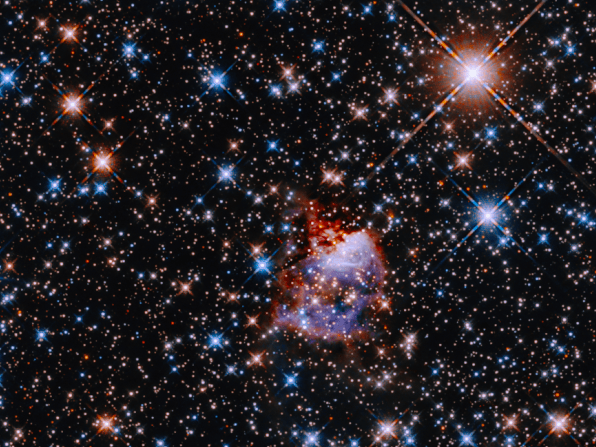 Black space illuminated by pink, blue and orange spacial activity. 