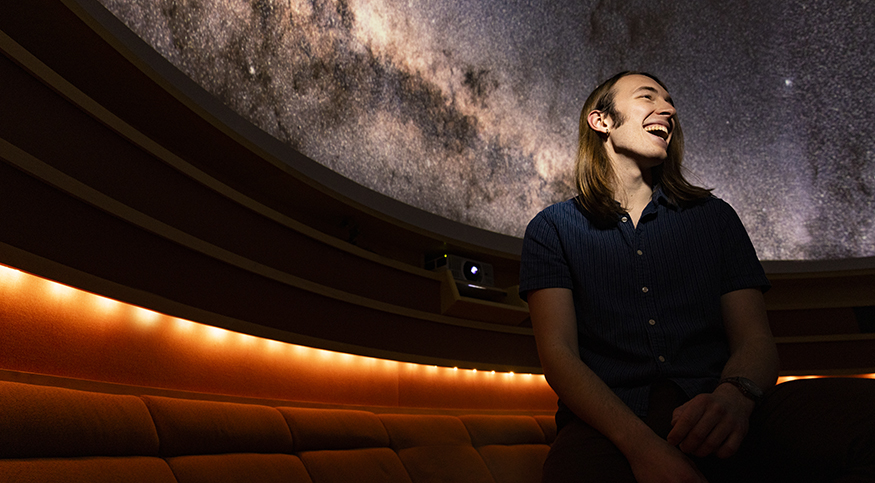 Tracking Comets, and Other Celestial Adventures Max Frissell in the UW Planetarium, with the starry "sky" visible behind him.