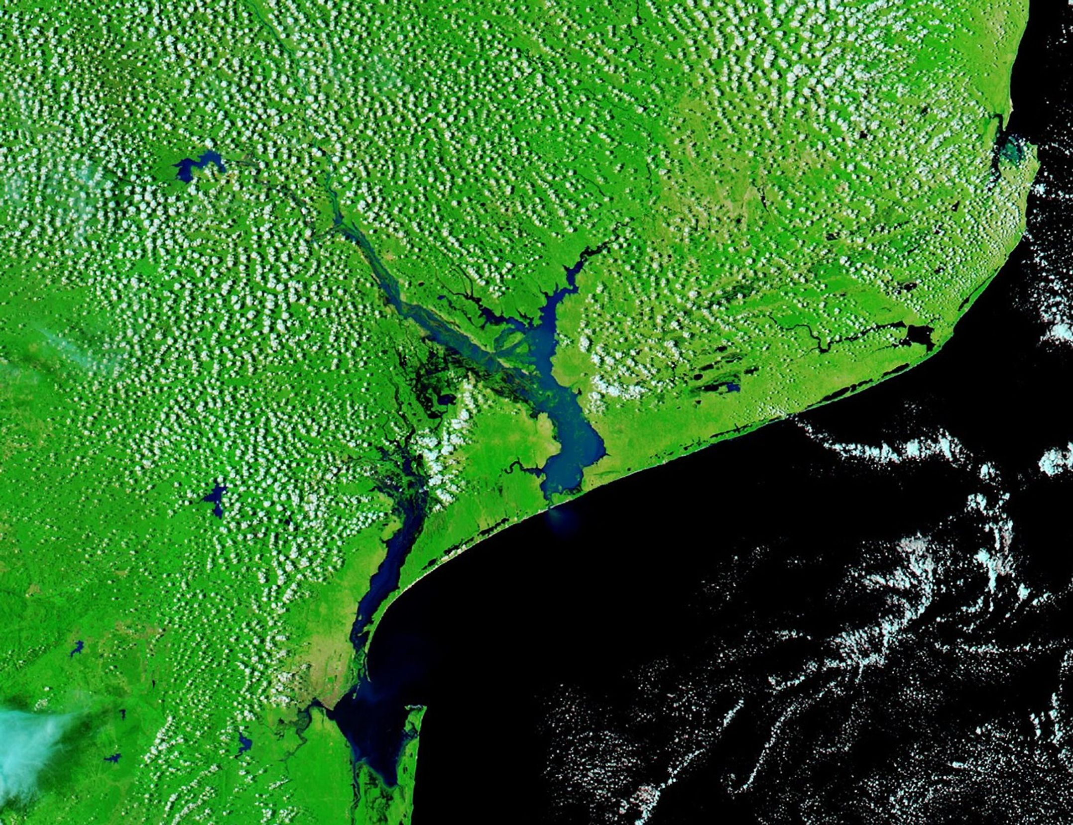 Water fills broad plains along the Incomati and Limpopo Rivers in Mozambique in a false-color image captured on January 25, 2026. Floodwaters appear dark blue, while the surrounding landscape is green. Labels mark the locations of Xai-Xai and Maputo.
