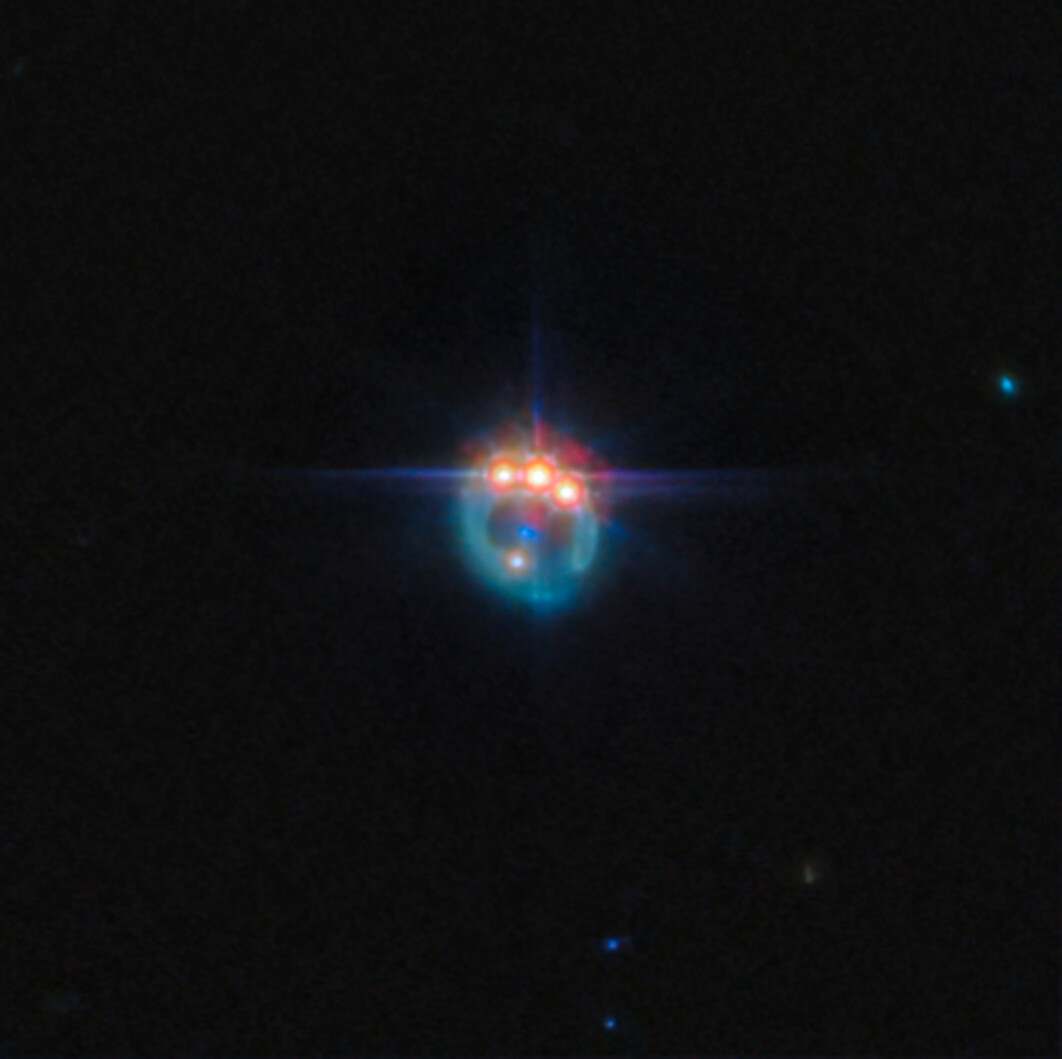 A bright, colorful object with blue, red, and orange lights appears against a dark space background, emitting star-like flares and a glowing halo—a scene reminiscent of a JWST reveal of the universe.
