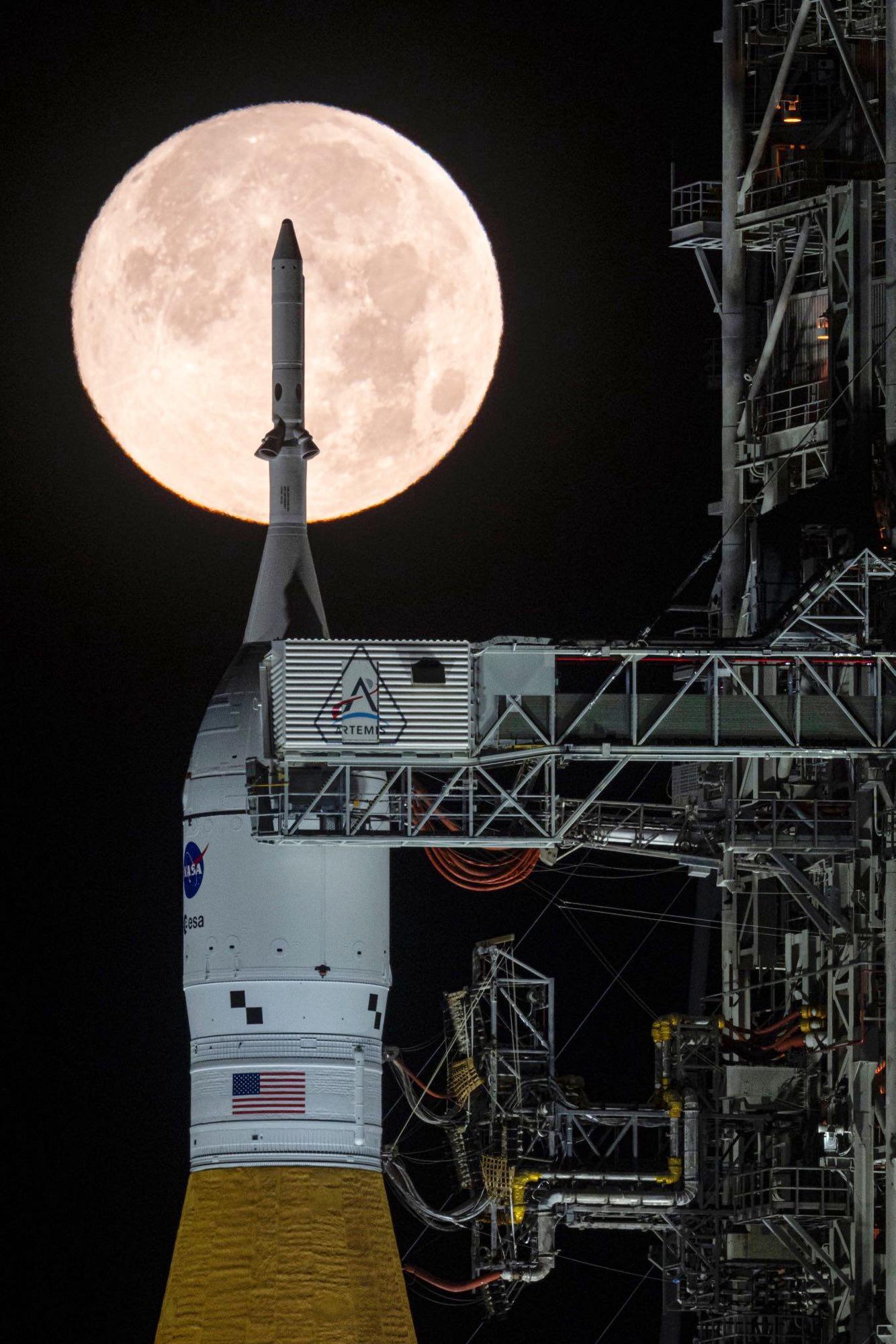 A full moon is seen shining over NASA’s SLS (Space...