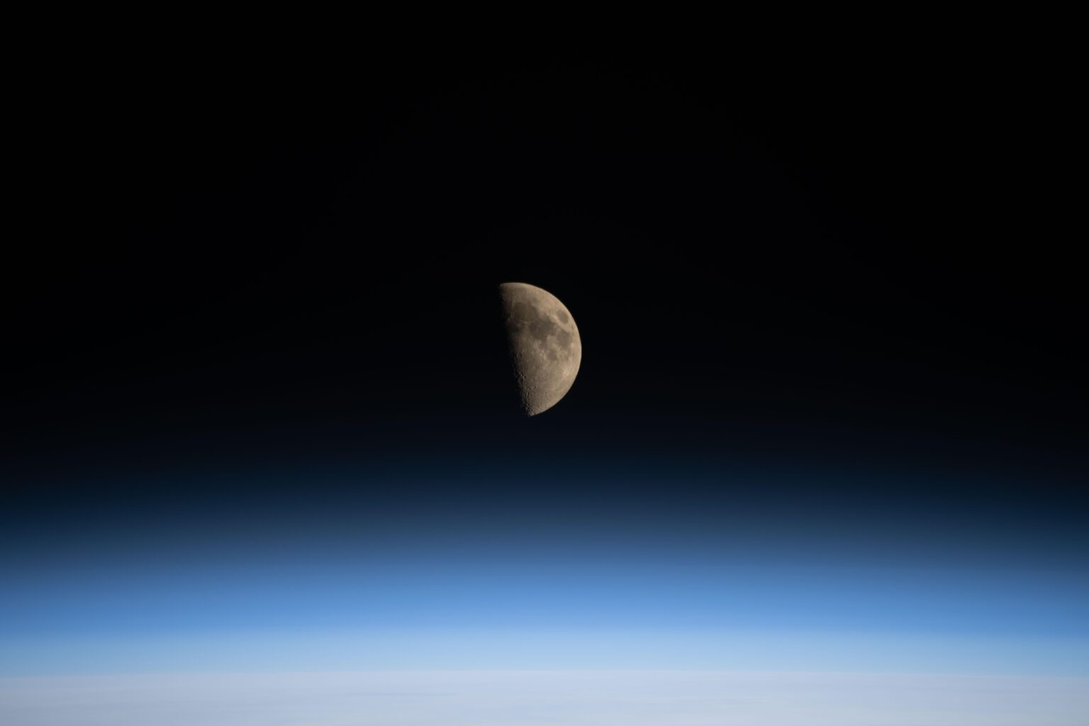The first‑quarter Moon sets over the Pacific Ocean, imaged from the ISS by Astronaut Chris Williams