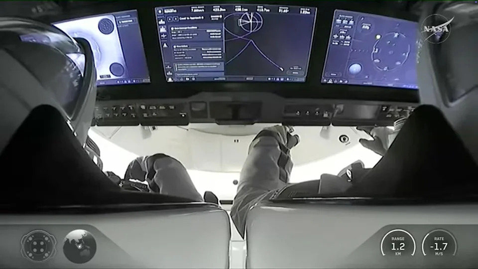 A camera inside the Crew Dragon capsule looks over the shoulders of commander Jessica Meir, left, and Jack Hathaway as they monitor cockpit displays during final approach to the International Space Station. Feb. 14, 2026.  / Credit: SpaceX