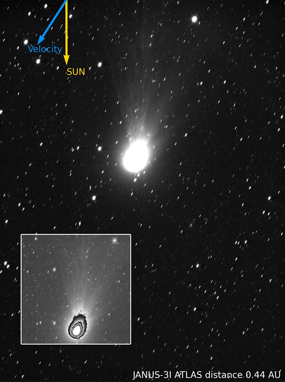 A photograph of a comet and its tail in space. Close-up reveals layers in its halo