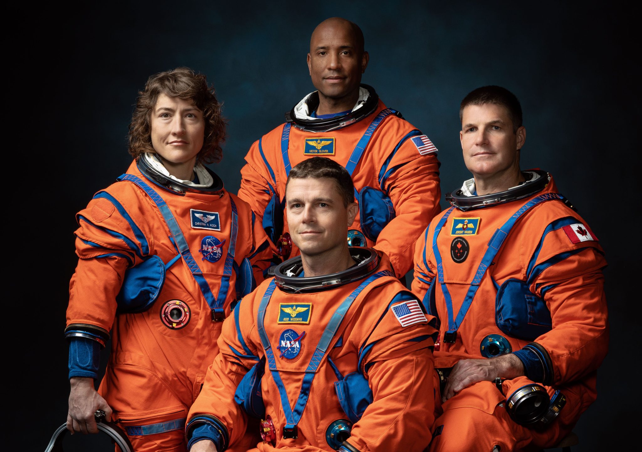 NASA astronauts Reid Wiseman, Victor Glover, and Christina Hammock Koch, and CSA astronaut Jeremy Hansen pose in their orange flight suits for a photo.
