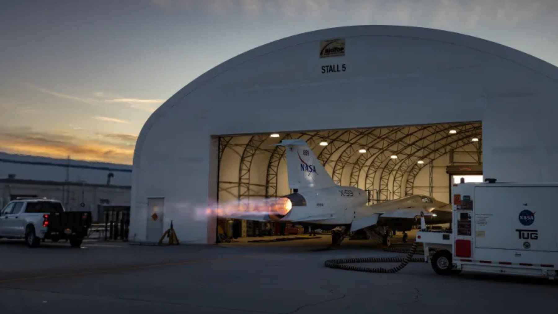 NASA’s X-59 quiet supersonic jet runs its engine with an afterburner plume during a ground test outside a hangar in Palmdale, California.