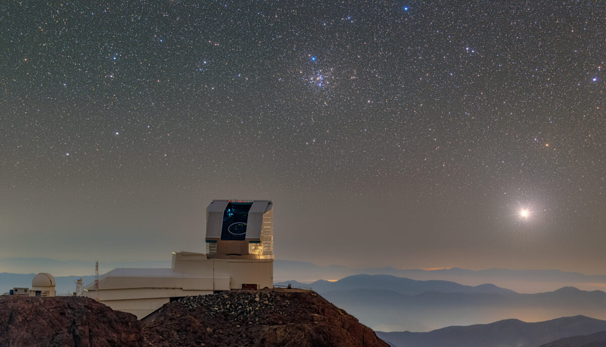 A large telescope sits on a mountain top beneath a starry night sky.