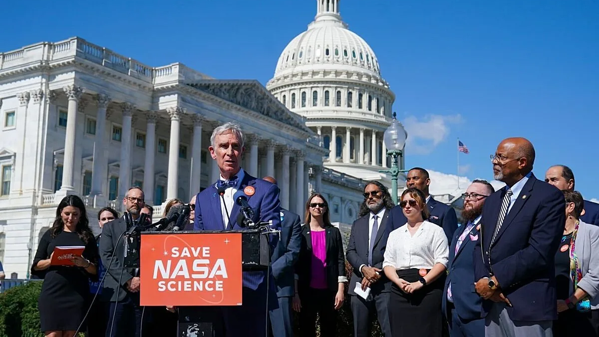 A large group of people stand on the steps of the U.S. Capitol in bright sunlight.