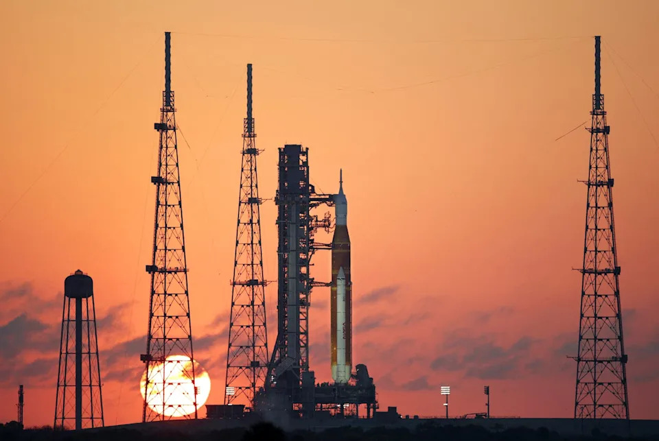 A rocket on a launchpad with a rising sun in the background
