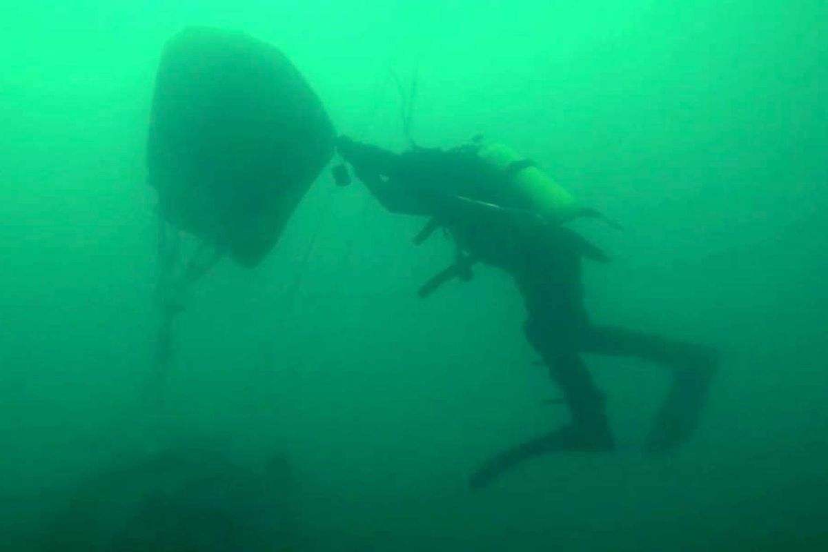 This handout video grab released by Russian Emergency Ministry on December 28, 2016, shows shows a diver lifting a piece of the crashed military plane carrying 92 people, including dozens of members of the Red Army Choir, during searches in the underwater area outside Sochi, in the Black Sea