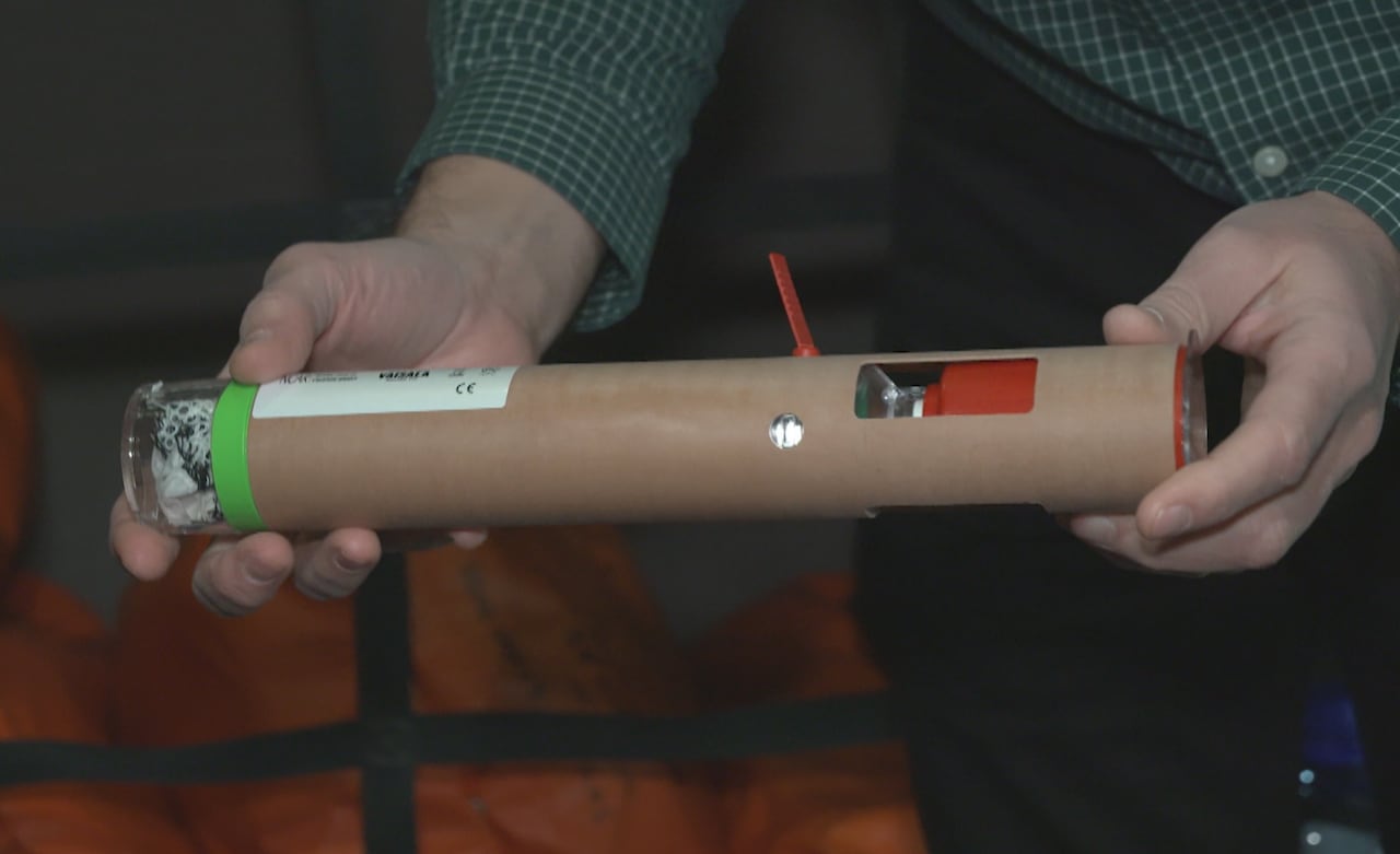A man holds what looks like a cardboard tube