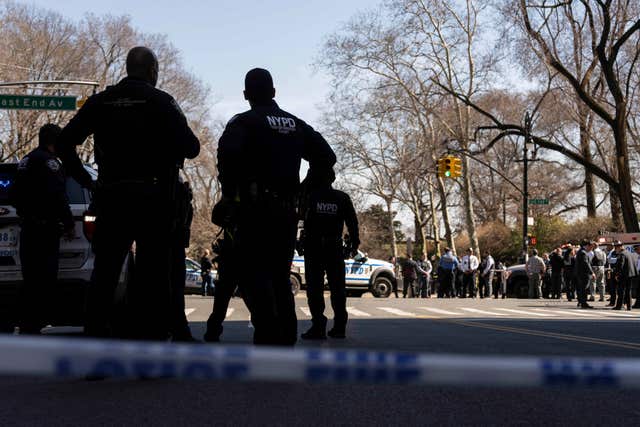 NYPD officers stand within a cordon on a street