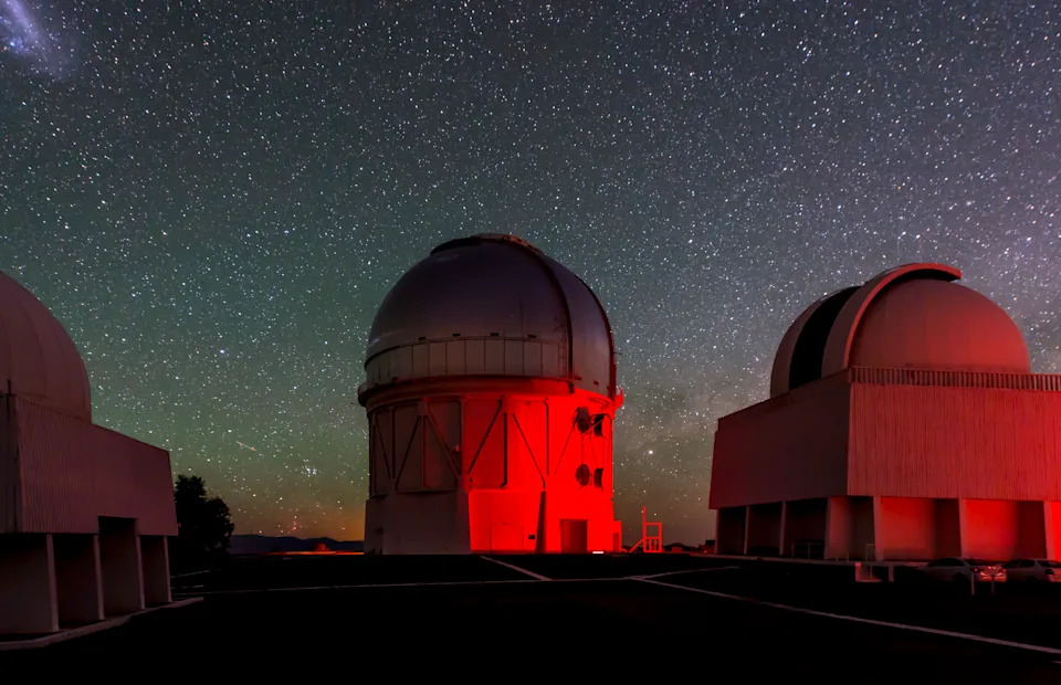 A dome washed in red light under the night sky.