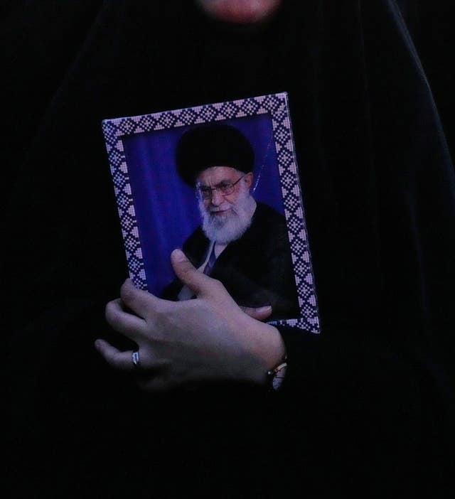 A person holding a framed photo of Iranian Supreme Leader Ayatollah Ali Khamenei