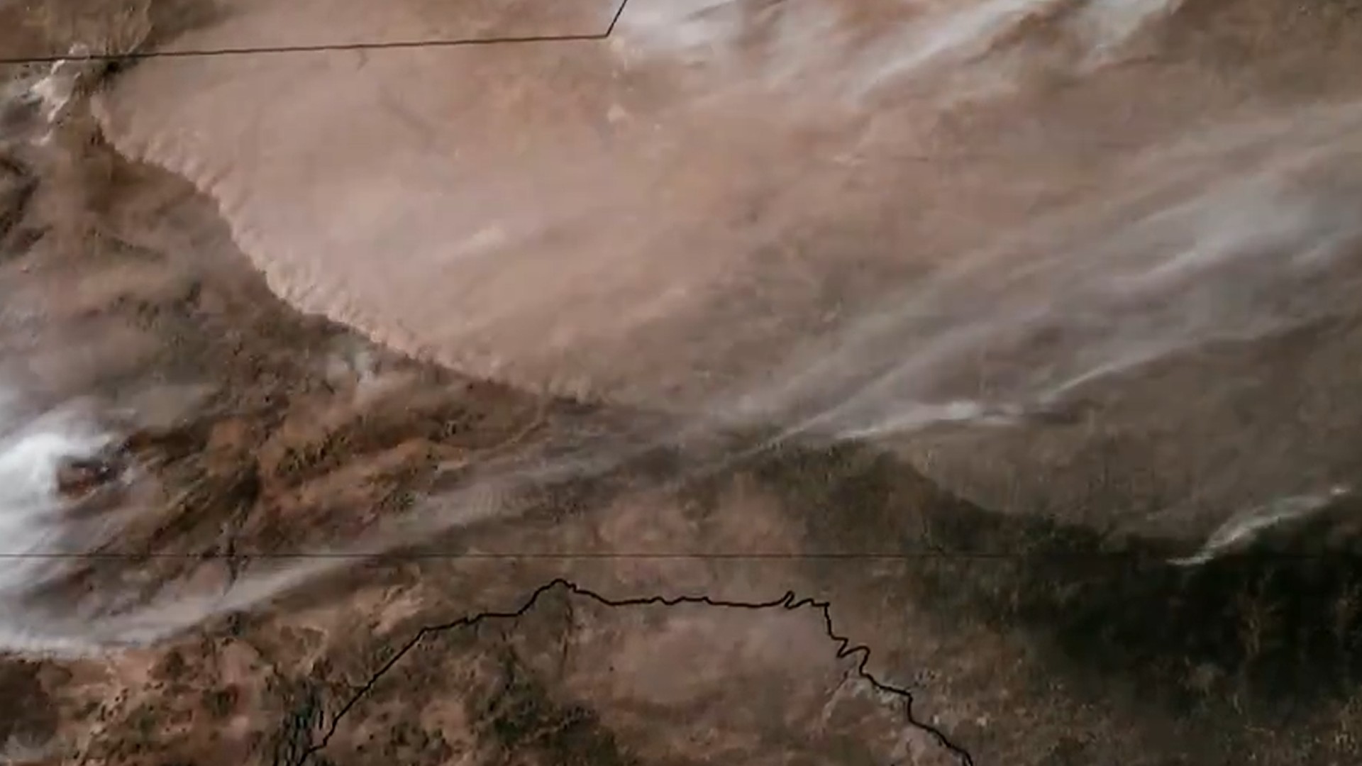 a line of light brown wispy dust races across the ground in a satellite view