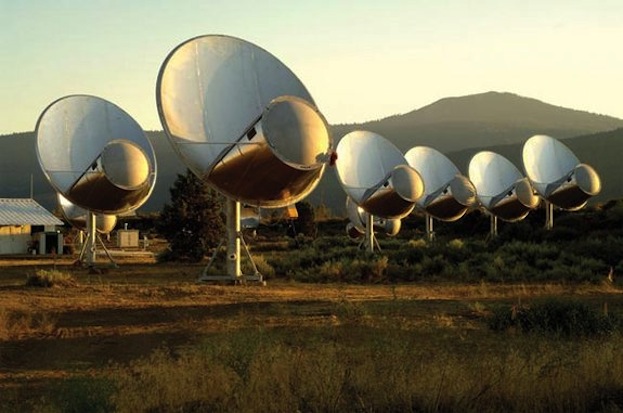 an array of round antenna dishes aim skyward amid a desert landscape