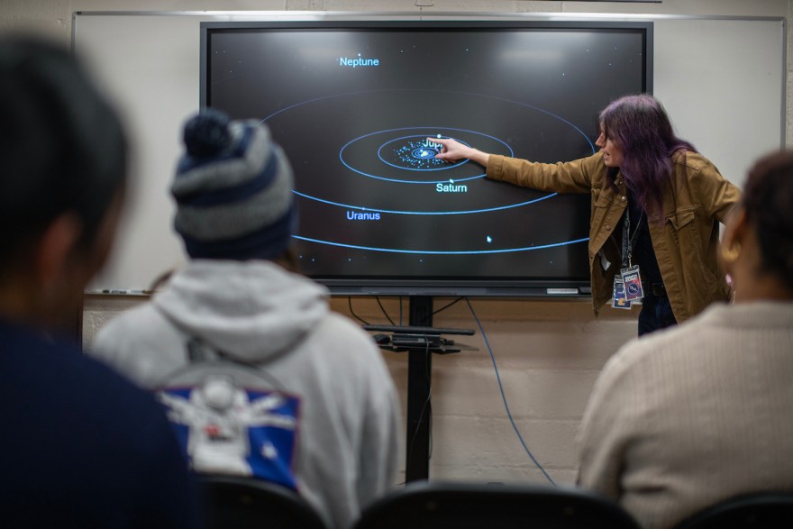 Steven Kline points to a digital display of the solar system during a lecture at the UTC Observatory Star Party as audience members watch from their seats.
