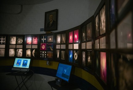 The interior of the observatory shows a curved wall lined with framed astronomical photographs and informational displays.
