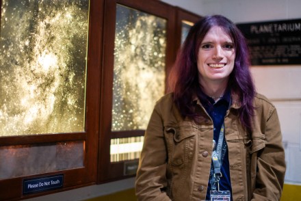 An observatory presenter stands near framed space images inside the UTC Observatory.