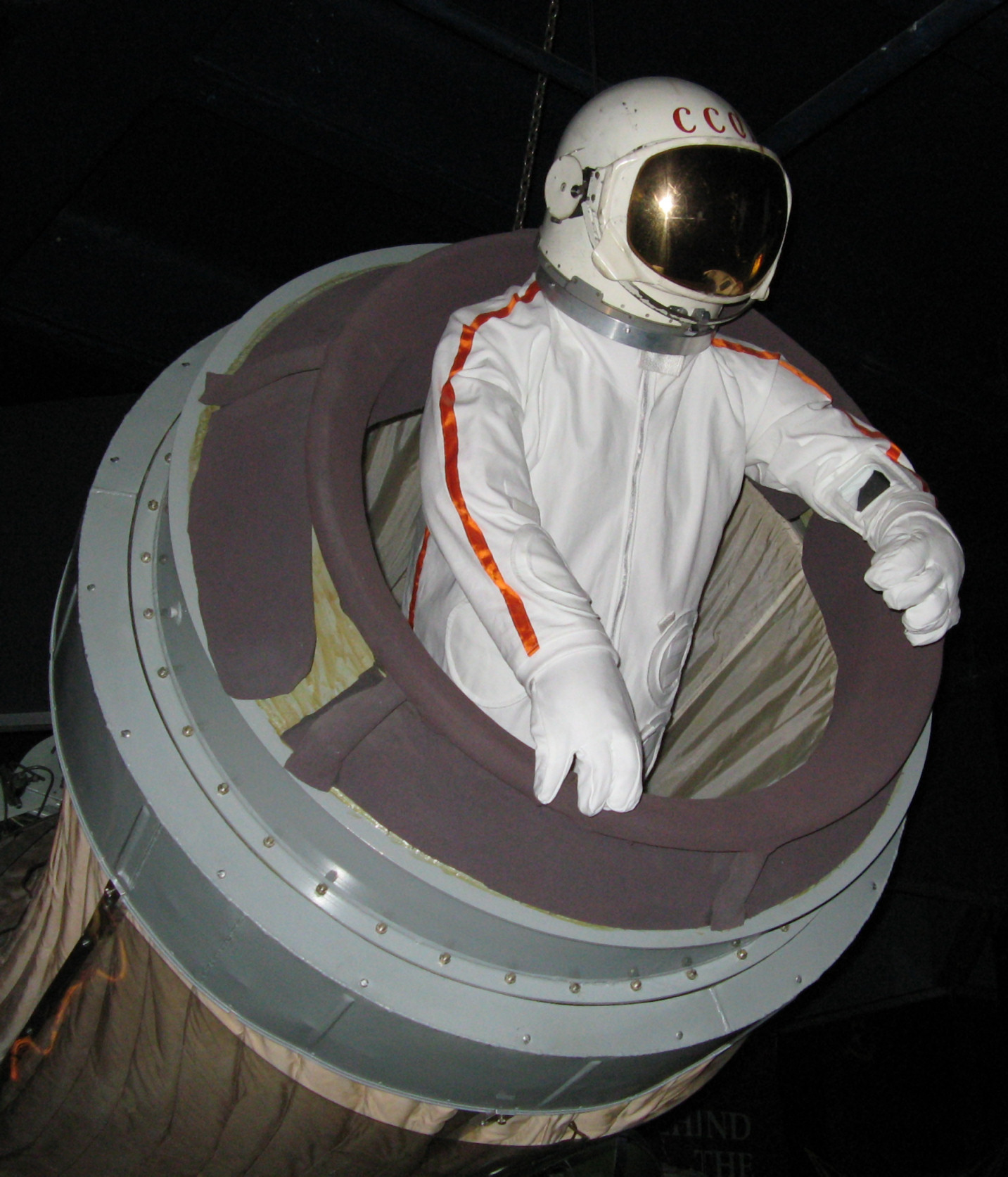 A museum installation showing a cosmonaut suit exiting the airlock of a Voskhod spacecraft.