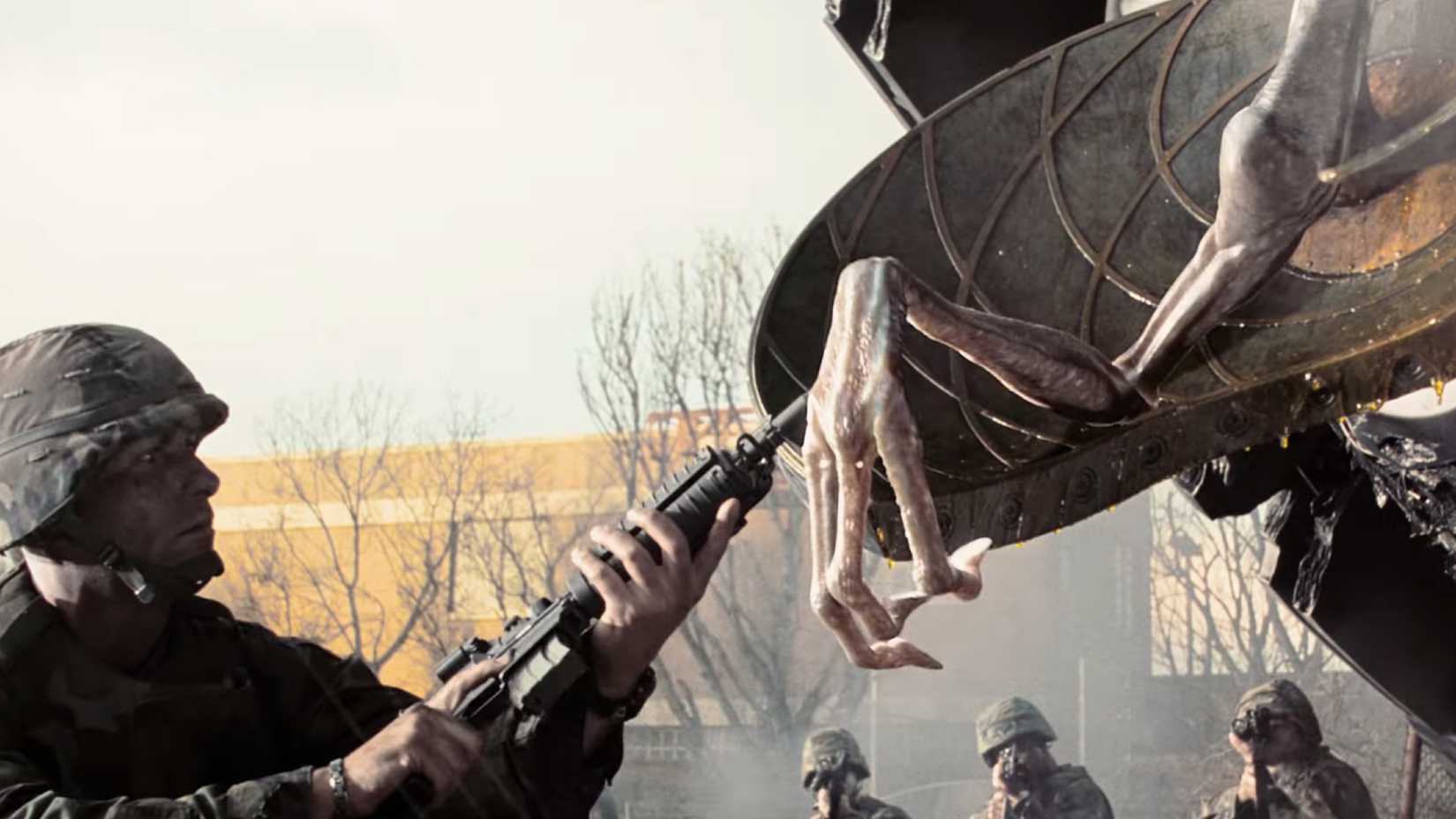 A soldier plays with a lifeless alien hand with the barrel of his rifle in War of the Worlds