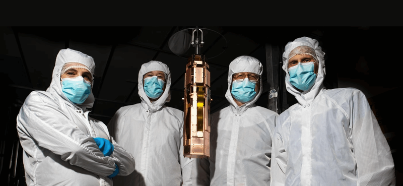 From left, SLAC research technical manager Concetta "Tina" Cartaro, staff scientist Paul Brink, senior staff scientist Richard Partridge and Santa Clara University physics professor Betty Young with the fourth, and final, SuperCDMS tower, in the SLAC Building 033 clean room. (CREDIT: Jacqueline Ramseyer Orrell/SLAC National Accelerator Laboratory)