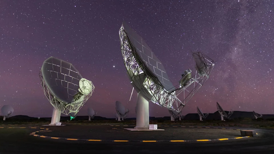 A photo of two radio dishes pointed up at the night sky
